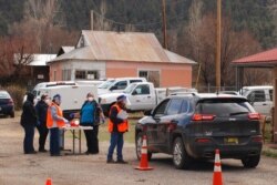 FILE - Medical workers and volunteers administer the coronavirus vaccine at a drive-through clinic in Mora, N.M., April 20, 2021. New Mexico is the latest U.S. state to offer cash lottery prizes in a bid to increase vaccination rates.