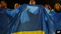 People wave a Ukrainian flag in support of the country in Kramatorsk, Ukraine, Feb. 23, 2022. U.S. President Joe Biden announced the U.S. was ordering heavy financial sanctions against Russia, for what he called the "beginning of a Russian invasion of Ukraine."