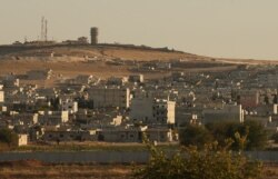 In this photo taken from the Turkish side of the border between Turkey and Syria, in Suruc, southeastern Turkey, a U.S forces outpost is seen on a hilltop, top left, outside Ayn al-Arab or Kobani, Syria, Oct. 12, 2019.