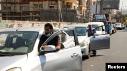 Orang-orang mendorong mobil mereka karena kekurangan bahan bakar, di dekat sebuah pompa bensin di Dora, Lebanon, 17 Agustus 2021. (Foto: Reuters)
