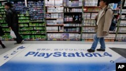 A shopper walks on the logo of Sony's PlayStation 4 at an electronics store in Tokyo, Dec. 25, 2014.