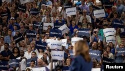 People raise signs in support of U.S. Vice President Kamala Harris as she speaks at a campaign event at West Allis High School in West Allis, Wisconsin, July 23, 2024. 