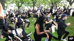 Anjel Newmann, 32, kneels while scanning her phone during a peaceful rally in Providence, R.I. on June 5. 