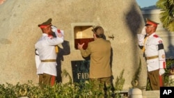 FILE - Cuba's President Raul Castro places the ashes of his older brother Fidel Castro into a niche in his tomb, a simple, grey, round stone about 15 feet high at the Santa Ifigenia cemetery in Santiago, Dec.4, 2016. 