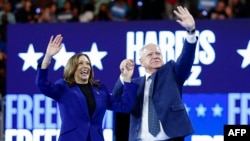 US Vice President and 2024 Democratic presidential candidate Kamala Harris and her running mate Minnesota Governor Tim Walz wave to the crowd after speaking at a campaign rally at the Fiserv Forum in Milwaukee, Wisconsin, August 20, 2024. (AP/Jacquelyn Martin)