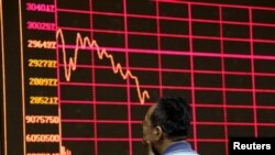 FILE - An investor looks at an electronic board showing stock information a brokerage house in Beijing, China, Aug. 26, 2015. 