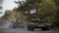 FILE - Russia-backed rebel tanks with a flag of the self-proclaimed Donetsk People's Republic are seen near Novoazovsk, eastern Ukraine, Oct. 21, 2015.