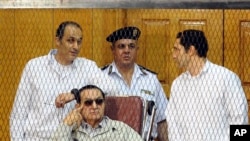 FILE - Former Egyptian President Hosni Mubarak, seated, and sons Gamal, left, and Alaa are seen attending a hearing in a Cairo courtroom Sept. 14, 2013.