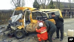 Rescuers inspect a school bus after it collided with a truck [not seen] in Yulinzi township of Zhengning county, Gansu province, November 16, 2011.