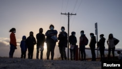 FILE - Asylum-seeking migrants from Central America await transport after crossing the Rio Grande River into the United States from Mexico on a raft in Penitas, Texas, March 12, 2021. 