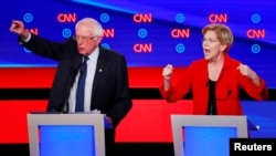 U.S. Senators Bernie Sanders (l) and Elizabeth Warren speak on the first night of the second 2020 Democratic presidential debate in Detroit, Michigan, July 30, 2019.
