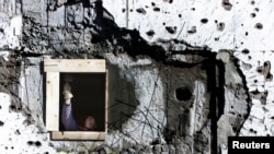 FILE - A worker repairs a war-shattered building at the former front line between two Bosnian entities in Sarajevo's suburb of Dobrinja, Nov. 20, 2000.