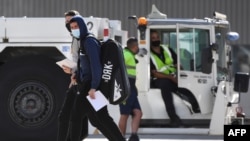 Tennis players and officials disembark from a flight after arriving in Melbourne on Jan. 14, 2021, to quarantine ahead of the Australian Open tennis tournament.