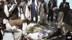 Relatives wrap the body of a civilian, who was killed during a clash of militants with policemen in Ghazni, southwest of Kabul, Afghanistan, May 1, 2011