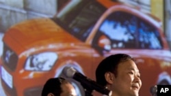 Li Shufu, right, chairman of Chinese automaker Geely, speaks while a photo of a Volvo car is projected on a screen during a press conference in Beijing, 30 Mar 2010