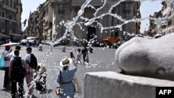 Orang-orang berjalan di Piazza del Popolo, Roma tengah saat gelombang panas melanda Italia, 17 Juli 2023.