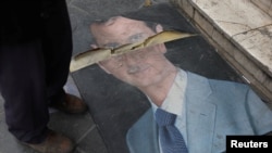 រូបឯកសារ៖ មនុស្ស​ម្នាក់​ឈរ​នៅ​ជាប់​នឹង​រូបភាព​របស់​លោក Bashar al-Assad នៅ​ក្នុង​ទីក្រុង​ដាម៉ាស ប្រទេស​ស៊ីរី នៅថ្ងៃទី១១ ខែធ្នូ ឆ្នាំ២០២៤។