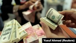 Seorang pegawai valas menghitung uang kertas dollar AS dan rupiah, di Makassar, Sulawesi Selatan, 31 Januari 2013. (Foto: Yusuf Ahmad/Reuters)