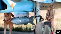 Russian military support crew attach a satellite guided bomb to SU-34 jet fighter at Hmeimim airbase in Syria, Oct. 3, 2015.
