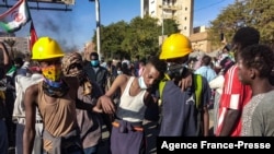 Sudanese youths help an injured demonstrator during a protest in the capital Khartoum against the army's October 25 coup, on Dec. 30, 2021.