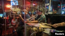The Catahoula Music Company performs behind protective plexiglass at Maison Bourbon as the coronavirus disease (COVID-19) restrictions are eased in New Orleans, Louisiana, March 13, 2021.