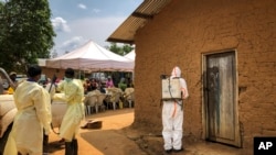  A worker from the World Health Organization decontaminates the doorway of a house on a plot where two cases of Ebola were found, in the village of Mabalako, in eastern Congo, June 17, 2019. 