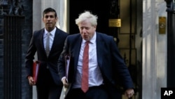 FILE - Britain's Prime Minister Boris Johnson, right, and Finance Minister Rishi Sunak, leave Downing Street to attend a cabinet meeting in London, Sept. 1, 2020. 