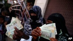 FILE - Women display paper currency after they received it in the form of assistance from the U.N. Children's Agency UNICEF, in Sana'a, Yemen, Nov. 14, 2015. 