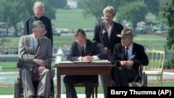 FILE - In this July 26, 1990 file photo, President George H. W. Bush signs the Americans with Disabilities Act during a ceremony on the South Lawn of the White House.