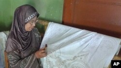 A woman uses a batik tool to write wax onto fabric at the IOM workshop she shares with other textile-makers from Kebon, Central Java, 4 April 2010