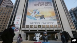 People pass a banner promoting the upcoming 2018 Pyeongchang Winter Olympic as official mascots, a white tiger 'Soohorang' for the Olympic, and the Asiatic black bear "Bandabi" for the Paralympic (Bottom-R) are displayed in downtown in Seoul, South Korea, Jan. 9, 2018.