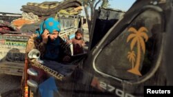 A woman who had just fled Deir el-Zour talks on a mobile phone beside a truck with her belongings at a camp in Ain Issa, north of Raqqa, Syria, Aug. 12, 2017.