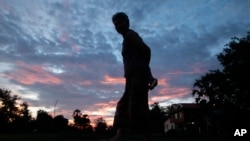 FILE - A Cambodian woman is silhouetted as she walks, on the outskirts of Phnom Penh, Cambodia.