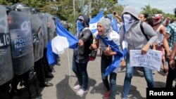 A demonstrator shouts slogans to riot police during a protest against Nicaraguan President Daniel Ortega's government in Managua, Sept. 23, 2018. 
