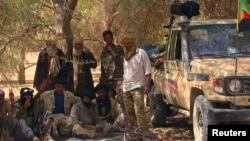 FILE - Fighters from the Tuareg separatist rebel group MNLA take shade under a tree in the desert near Tabankort, Mali, Feb. 13, 2015. 