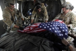 FILE - Upon landing after a helicopter rescue mission, Tech. Sgt. Jeff Hedglin, right, an Air Force Pararescueman, or PJ, drapes an American flag over the remains of the first of two U.S. soldiers killed minutes earlier in an IED attack.