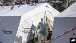 FILE - An employee of the Klinikum Bremen-Ost walks in protective clothing near, where coronavirus tests are being administered, in Bremen, Germany, March 16, 2020.