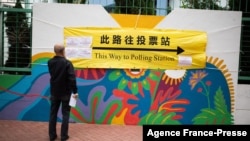 A man looks at a banner outside a polling station during the Legislative Council election in Hong Kong's Hung Hom area, Dec. 19, 2021. 