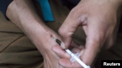 FILE - A man injects himself with heroin using a needle obtained from the People's Harm Reduction Alliance, the nation's largest needle-exchange program, in Seattle, Washington. 