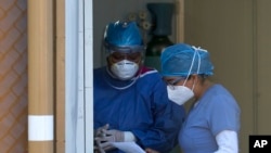Medical workers look over paperwork at the entrance to the COVID-19 triage area at the Mexico General Hospital, in Mexico City, May 12, 2020. 