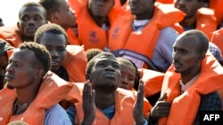 Des migrants et des réfugiés assis sur un bateau attendent d'être secourus par le Topaz Responder, un navire de sauvetage géré par l'ONG maltaise "Moas" et la Croix-Rouge italienne, le 4 novembre 2016 au large des côtes libyennes.