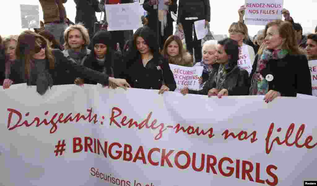 Former French first ladies Carla Bruni-Sarkozy (left) and Valerie Trierweiler (right) stand with politicians and entertainment artists holding a banner that reads &quot;Leaders, bring back our girls&quot; during a demonstration near the Eiffel Tower in Paris, May 13, 2014.