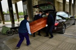 Undertakers wearing protection masks to protect from the coronavirus carry a coffin to a burial at San Jose cemetery in Pamplona, in Pamplona, northern Spain, April 13, 2020.