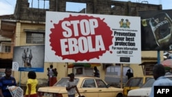 FILES - People walking past a billboard reading "Stop Ebola" in Freetown, Sierra Leone, Nov. 7, 2014. 