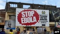 FILES - People walking past a billboard reading "Stop Ebola" in Freetown, Sierra Leone, Nov. 7, 2014. 