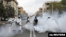 FILE - Firefighters wear protective face masks, amid fear of the coronavirus disease, as they disinfect the streets in Tehran, Iran, March 18, 2020. 