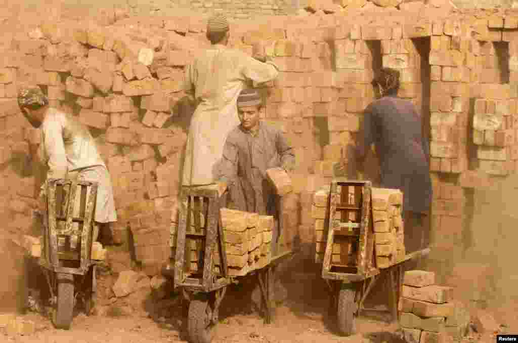 Laborers move baked bricks from an oven at a kiln on outskirts of Peshawar, Pakistan.
