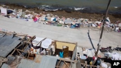 Jislene Jean Baptiste stands in her roofless home, damaged by Hurricane Matthew in Jeremie, Haiti, Friday, Oct. 7, 2016.