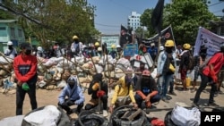 Protesters are seen gathered by a barricade during a crackdown by security forces on demonstrations against the military coup, in Yangon, Myanmar, March 20, 2021.