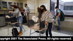 Students at Windsor Locks High School in Windsor Locks, Conn., clean their work areas at the end of class on March 18, 2021.